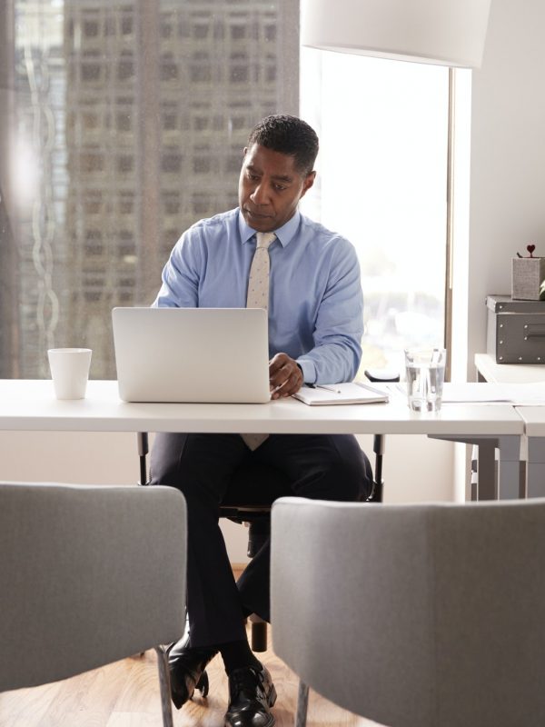 male-financial-advisor-in-modern-office-sitting-at-desk-working-on-laptop.jpg